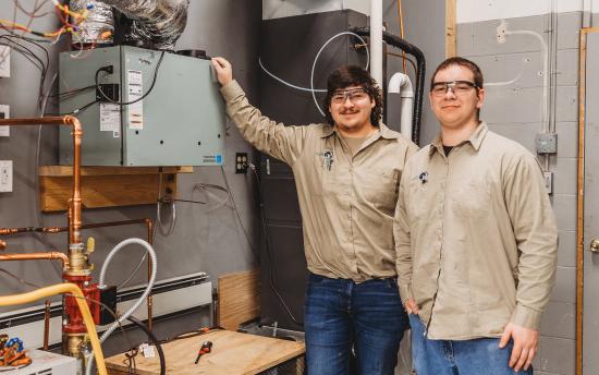 Two men smiling in front of metal hvac box